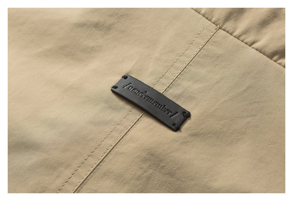 Close-up of beige fabric with a small black rectangular brand plate attached over a seam.