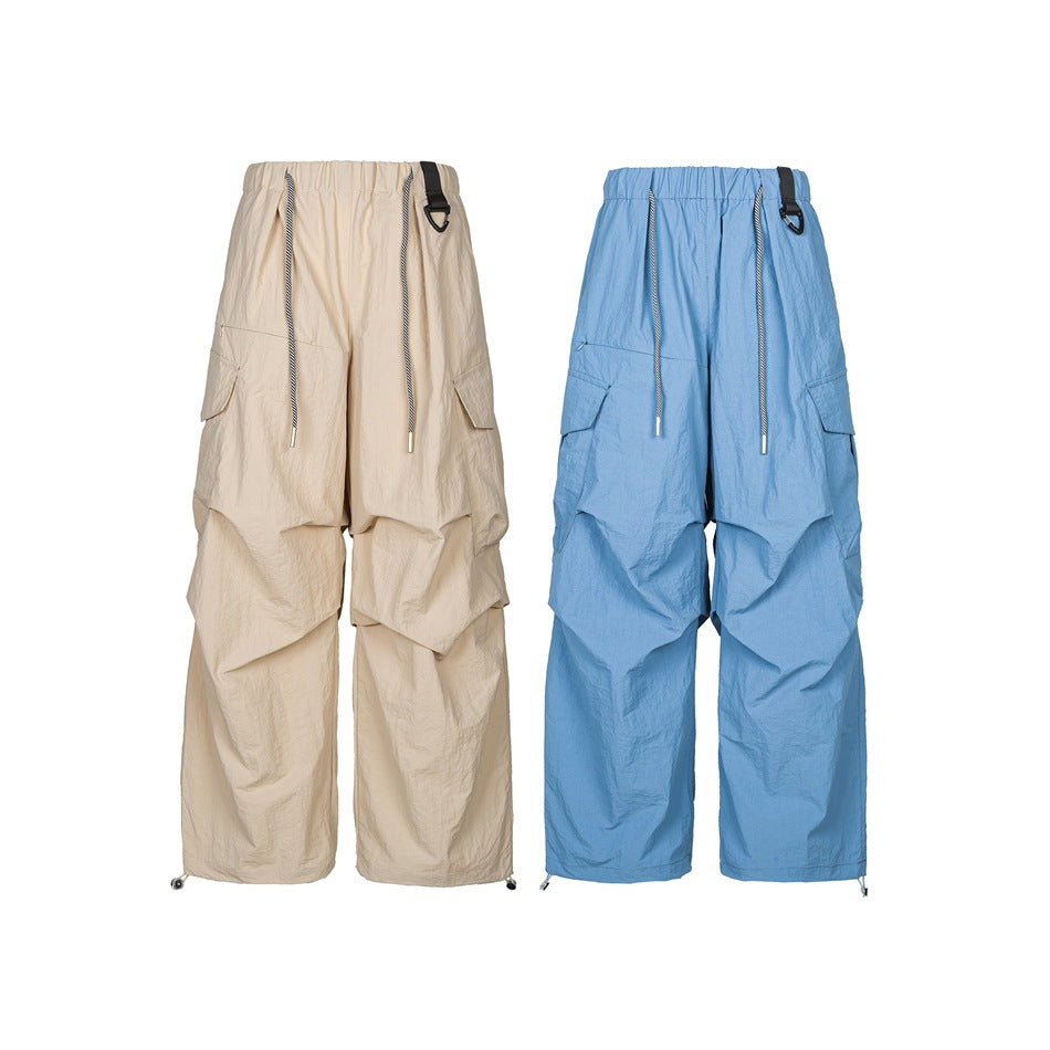 Front view of oversized cargo pants in beige and blue, with elastic waists, striped drawcords, and wide legs.