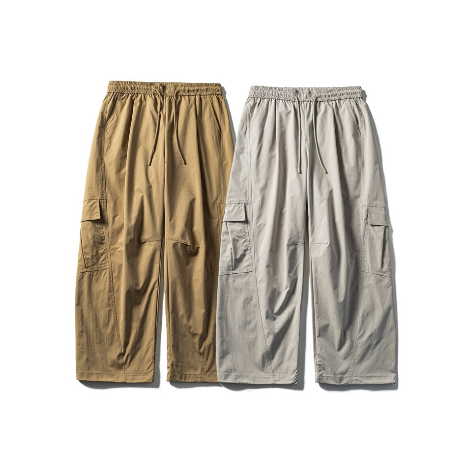 Front view of relaxed cargo pants in tan and light gray, with elastic drawstring waists and side flap pockets.