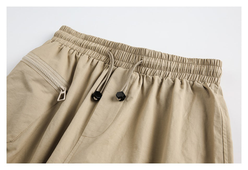 Close-up of tan pants with an elastic waistband, drawstrings, and a zippered pocket.