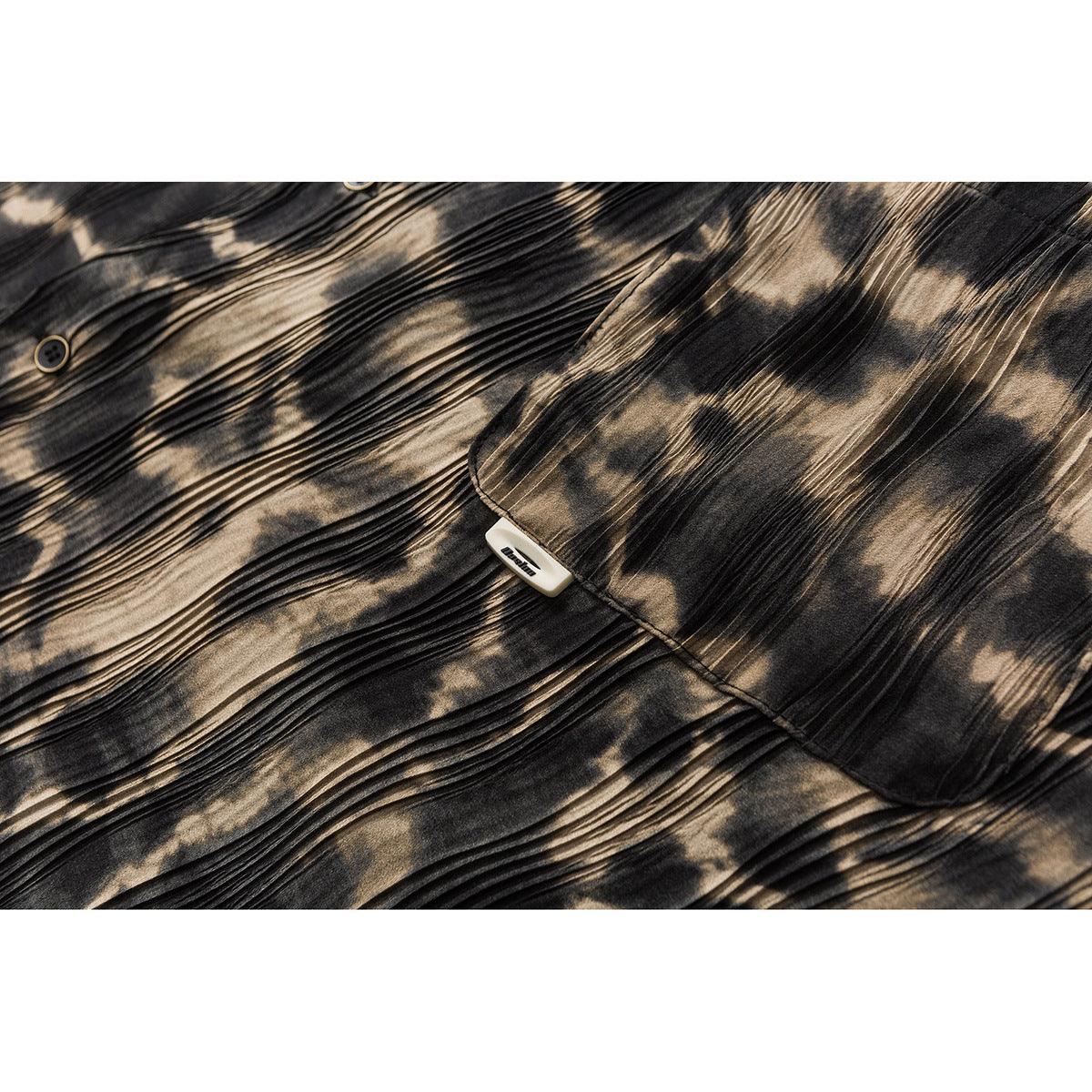 Close-up of a black and tan patterned shirt pocket, buttons, and attached garment tag.