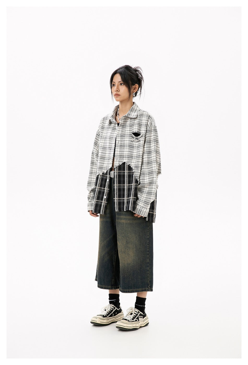Model wearing the beige and black plaid shirt open over faded wide-leg denim shorts and sneakers, front view