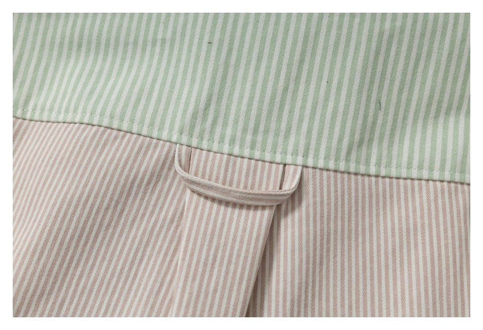 Close-up of green-and-white striped fabric overlapping pink-and-white stripes, with a small fabric loop.