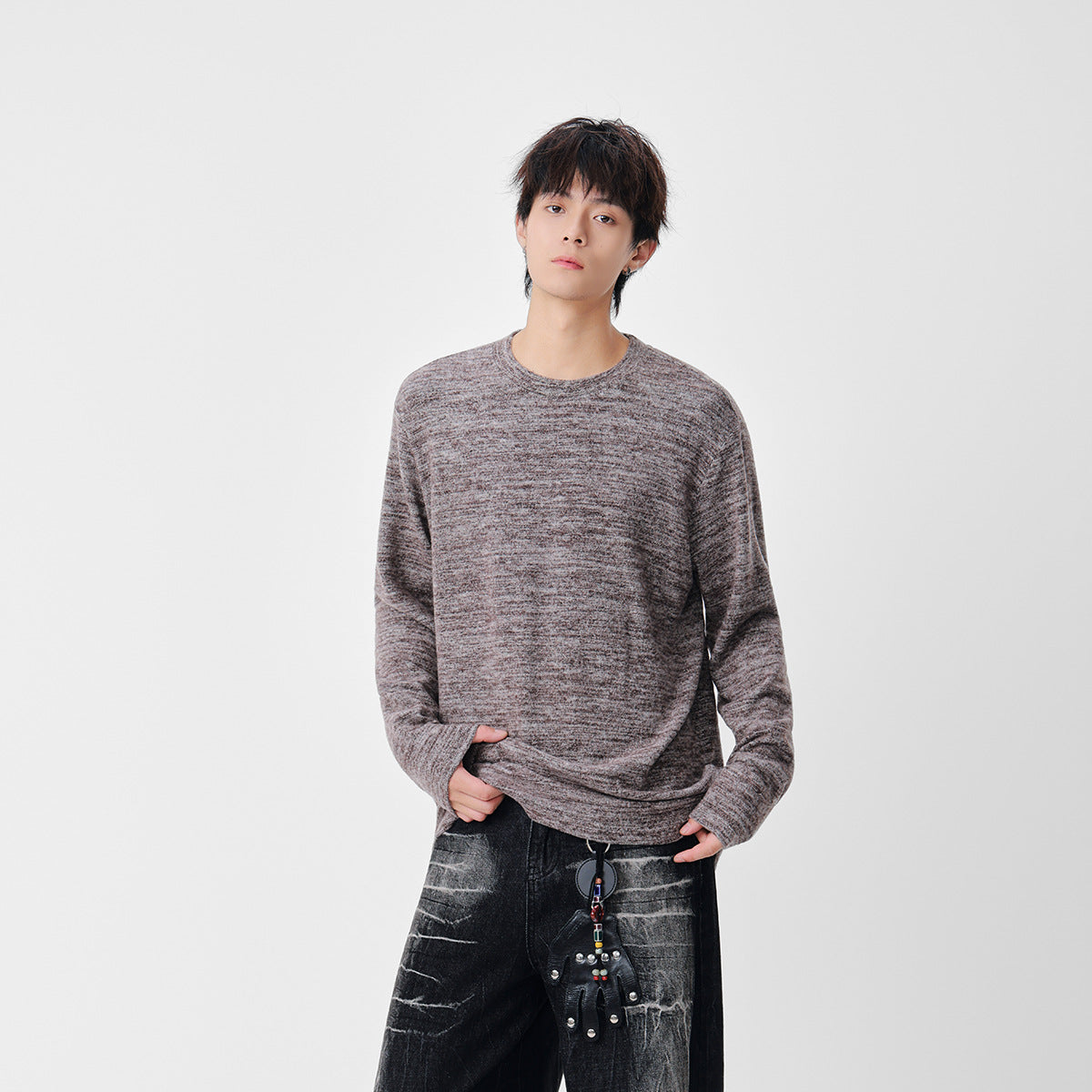 Model wearing a marled taupe-gray crew-neck sweater with long sleeves and dark jeans.