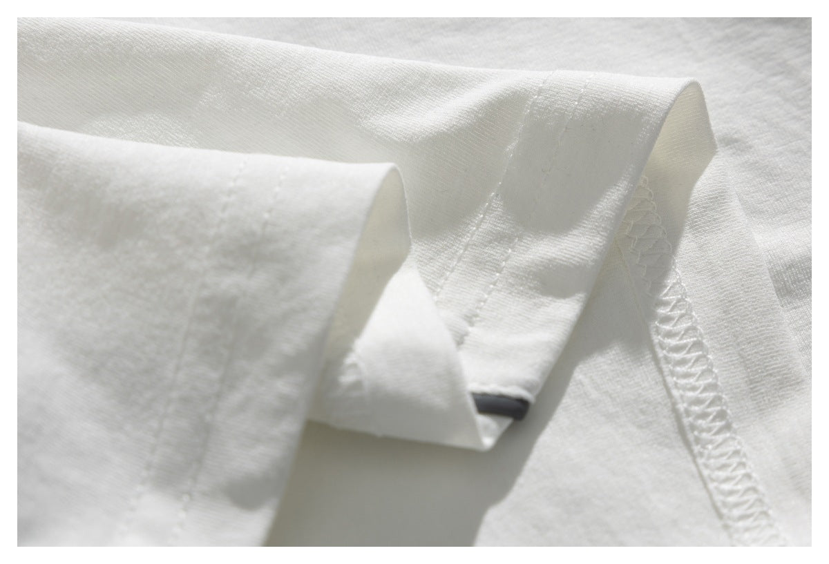 Close-up of a white garment hem showing folded fabric, stitching, and an overlocked seam.