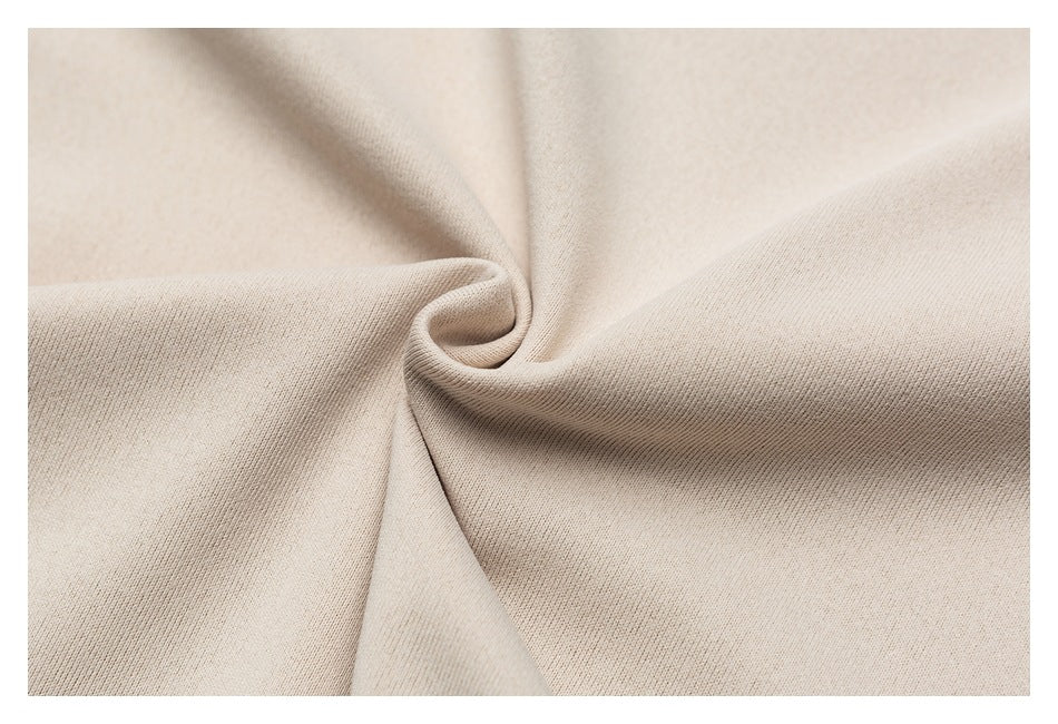 Close-up of beige fabric gathered into folds, showing its fine knit texture.