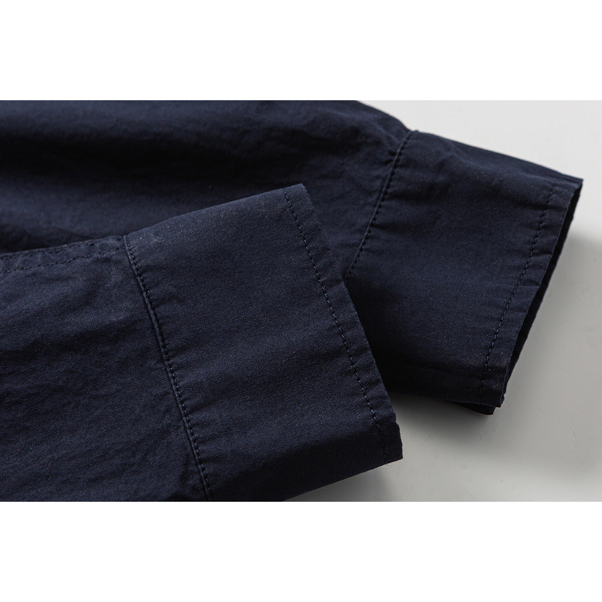 Close-up of the dark navy shirt's long sleeve cuffs and stitched seams.
