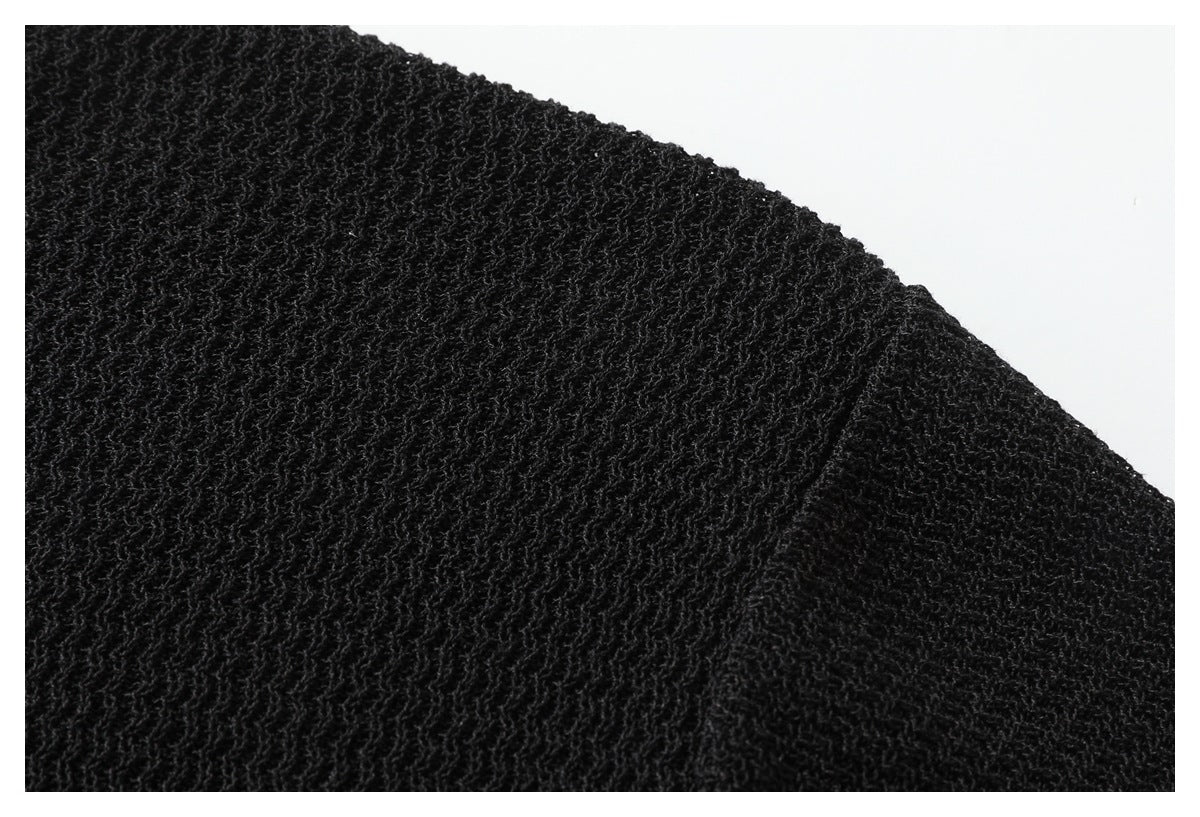 Close-up of the black polo's textured knit across a shoulder and sleeve seam.