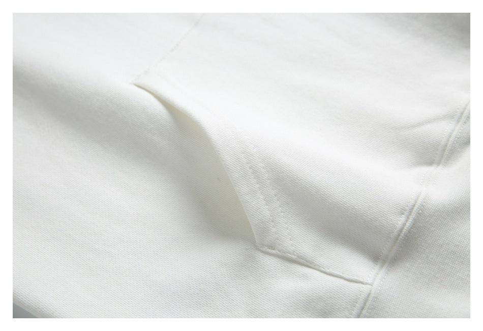 Close-up of white hoodie fabric and the stitched edge of its front kangaroo pocket.