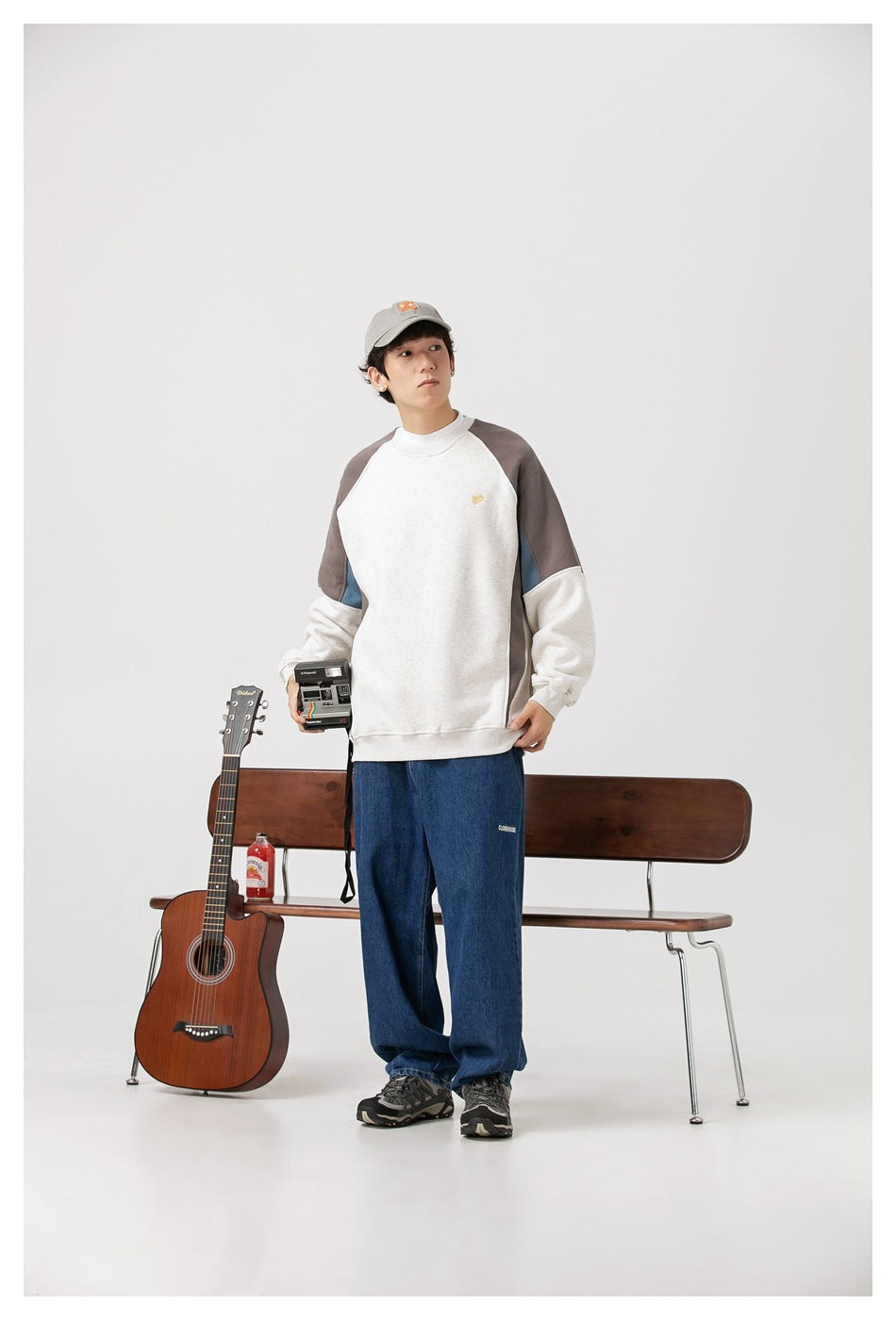 Model wearing an off-white color-block raglan sweatshirt with gray shoulders, blue side panels, and loose blue jeans.