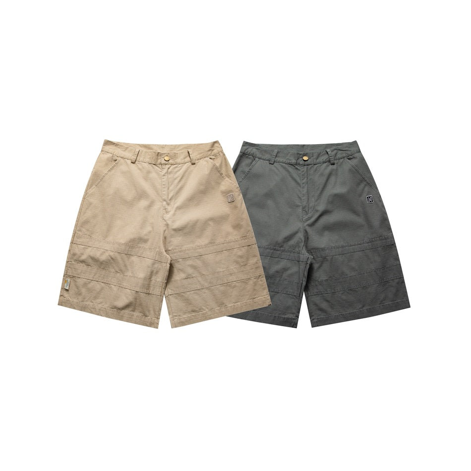 Front view of wide-leg shorts in tan and charcoal gray, with belt loops, button closures, and panel stitching.