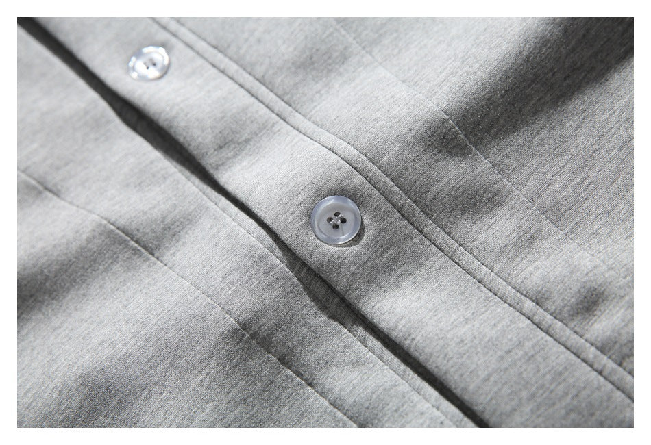 Close-up of a gray jacket button and the surrounding placket stitching.