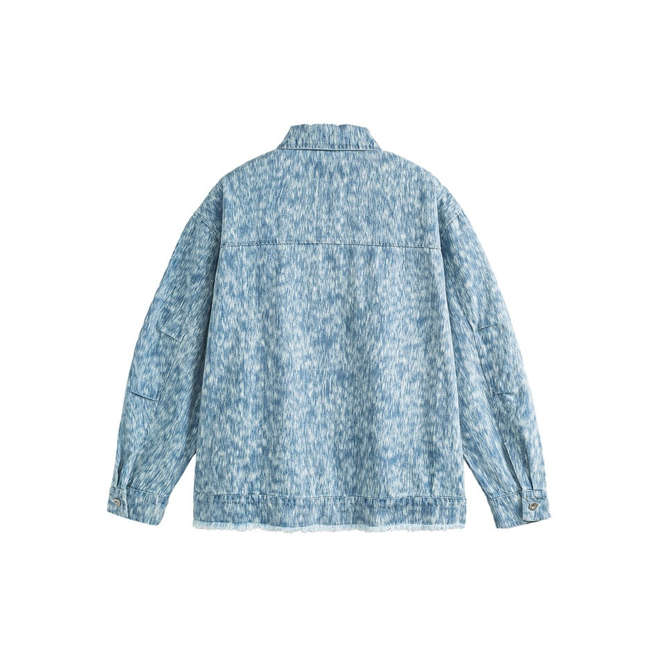 Back view of a light blue patterned jacket with a yoke seam, long sleeves, button cuffs, and a frayed hem.