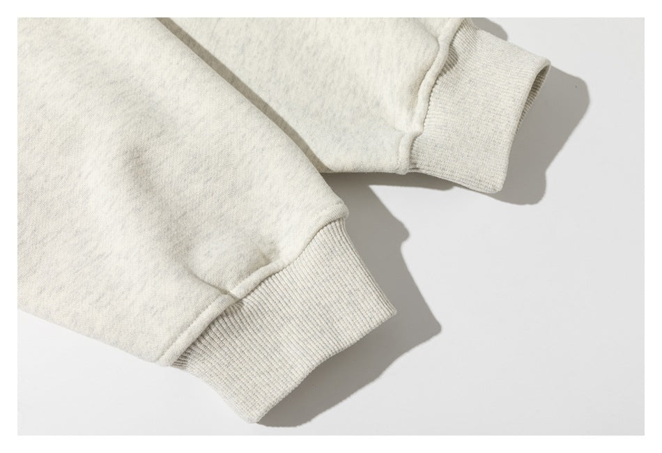 Close-up of two off-white sweatshirt cuffs with ribbed hems.