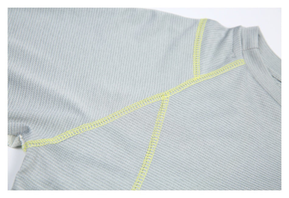Close-up of a pale gray textured shirt showing bright yellow seam stitching across the shoulder and sleeve.