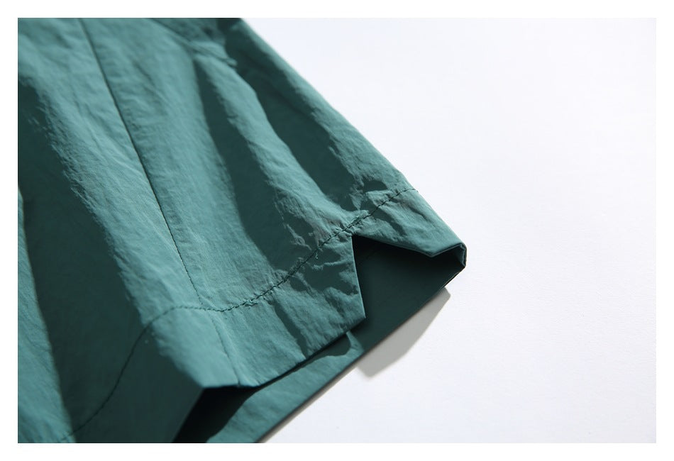 Close-up of a stitched side seam and hem on teal shorts against a white background.