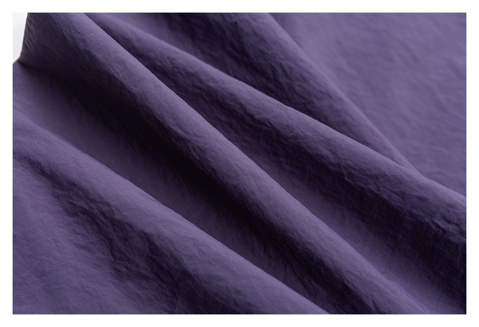 Close-up of the crinkled purple fabric on the pants, showing its surface texture.