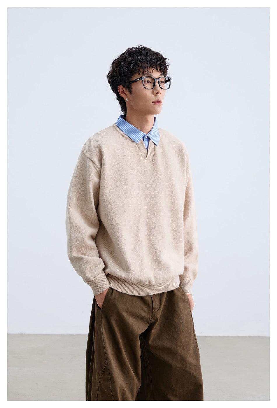 Three-quarter view of a model wearing a beige V-neck sweater with ribbed cuffs and hem.
