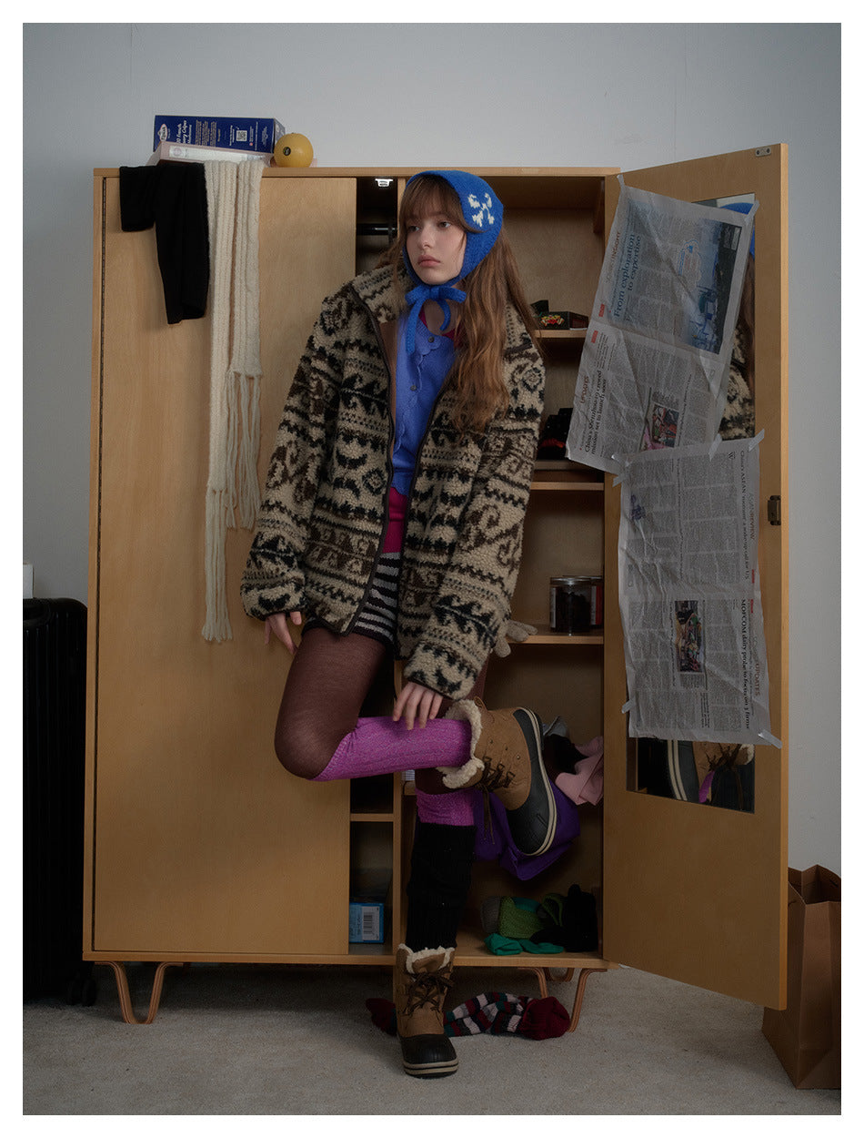 Model wearing a beige-and-black patterned zip jacket, blue knit bonnet, striped shorts, and colorful leg warmers.