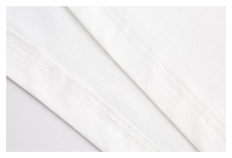 Close-up of white garment fabric showing an overlocked seam and stitched edge.