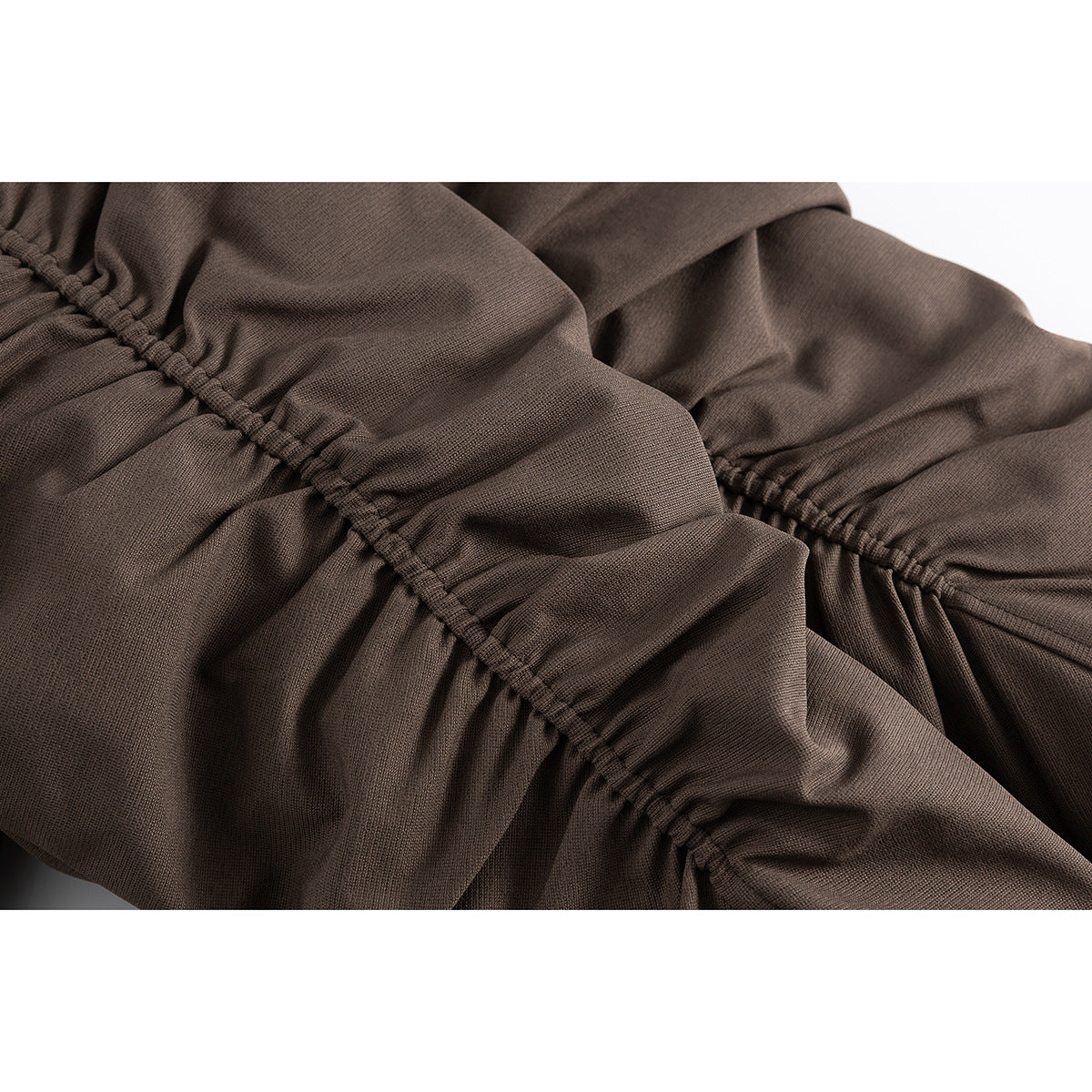 Close-up of brown jacket fabric with a gathered stitched seam and soft folds.