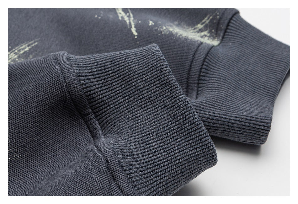 Close-up of a dark charcoal garment with ribbed cuffs and a pale abstract print.