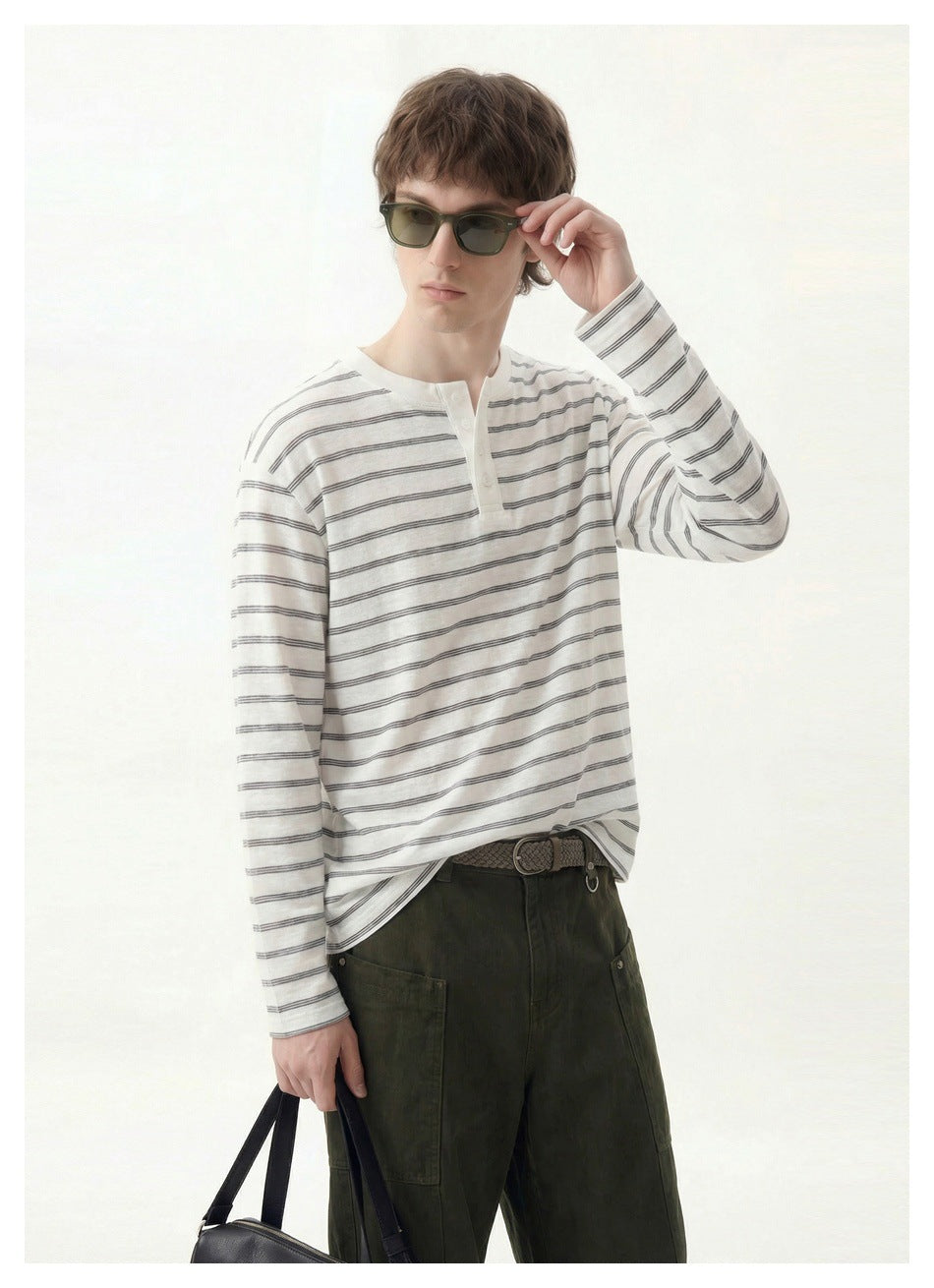 Model wearing a white long-sleeve Henley with thin dark horizontal stripes, shown from the front.