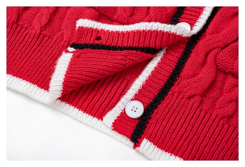Close-up of a red cable-knit cardigan with white buttons and white and black striped trim.