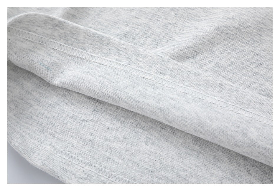 Close-up of stitching along a folded seam on light gray heather T-shirt fabric.