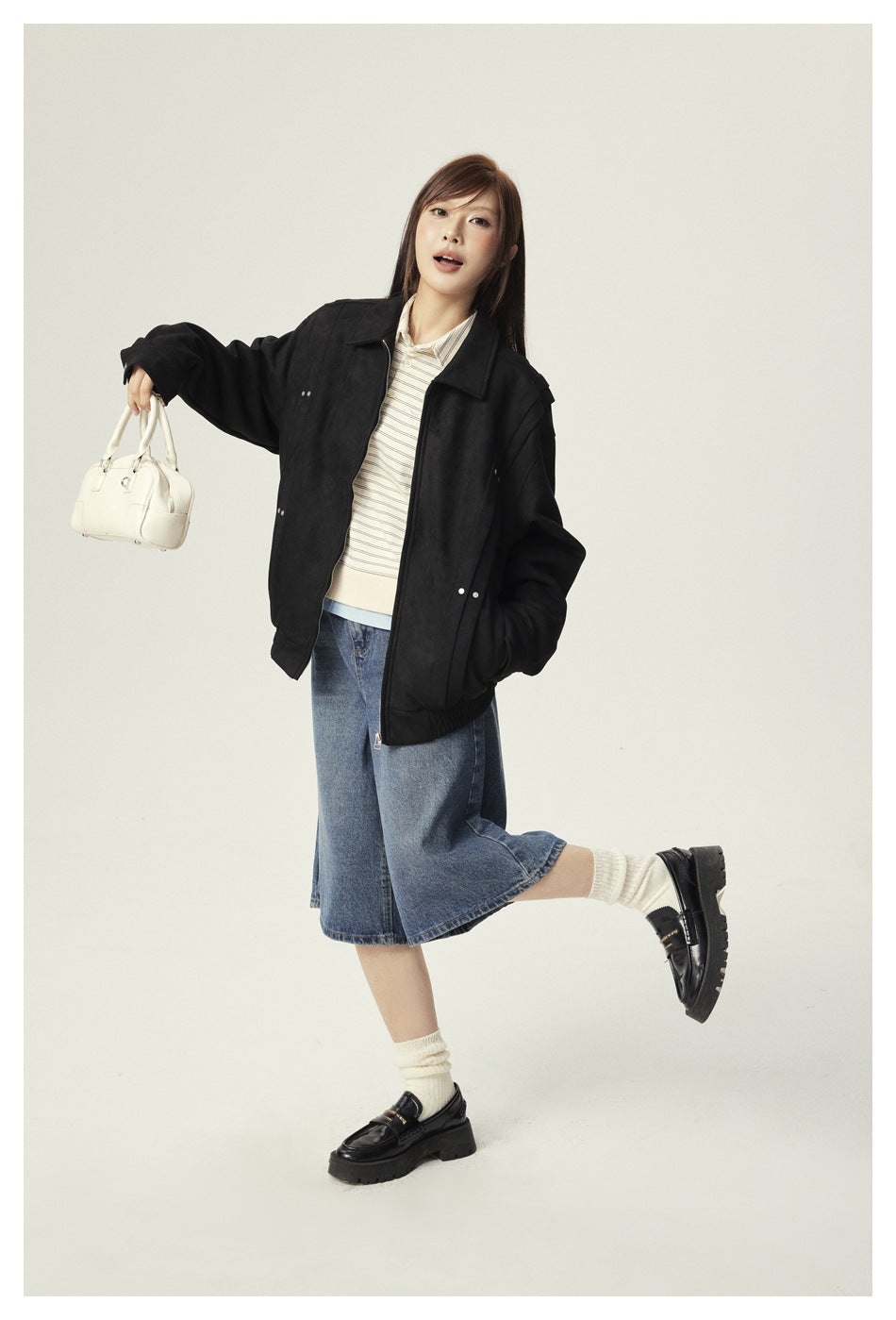 Model wearing an oversized black zip-front jacket with a pointed collar and gathered hem.