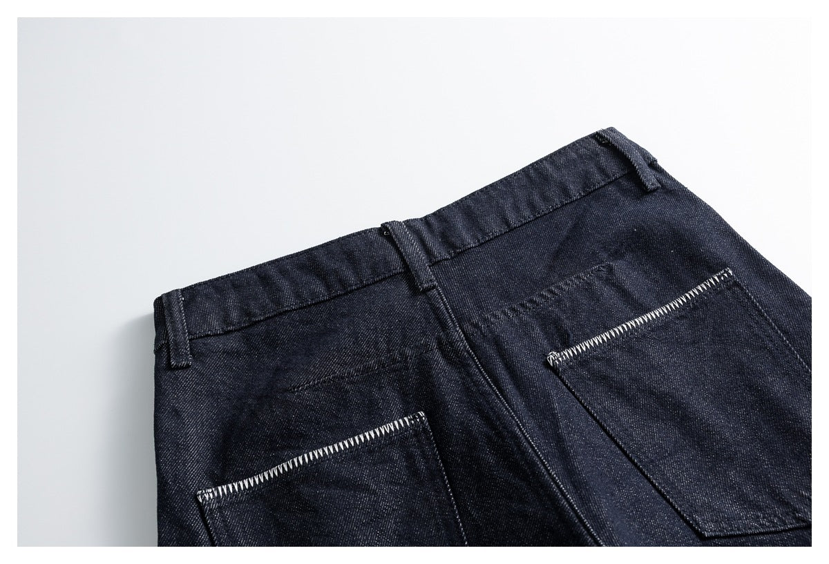 Close-up of the back waistband and two patch pockets on dark indigo trousers, with contrasting pocket-edge stitching.