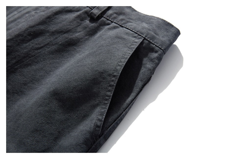 Close-up of charcoal trousers showing a belt loop, waistband and angled pocket opening.