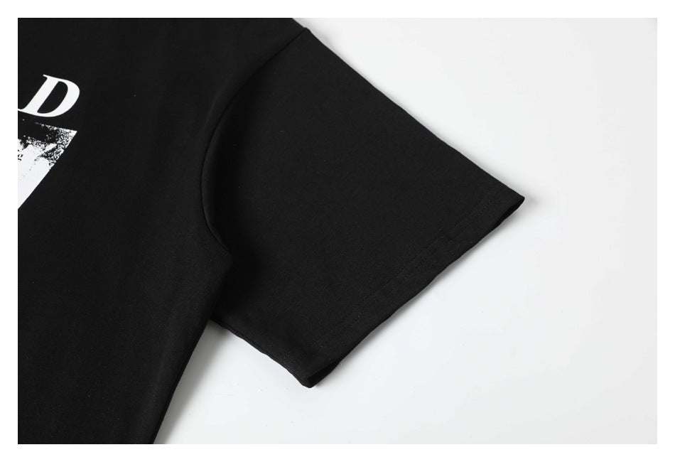 Close-up of a black T-shirt sleeve and partial white printed graphic on a white background.