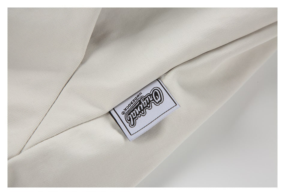 Close-up of off-white jacket fabric and a sewn rectangular label with an English logo.