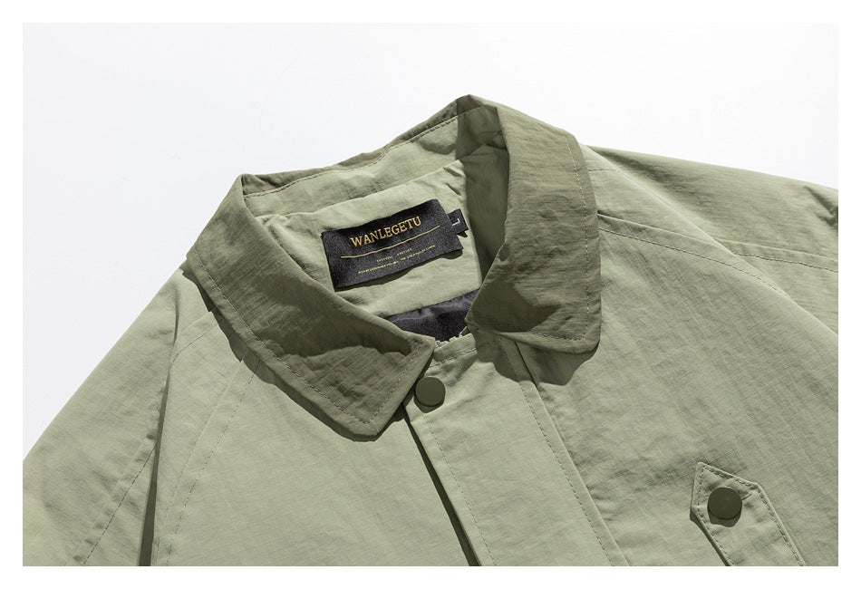 Close-up of an olive-green jacket's pointed collar, snap-button placket, chest pocket, and sewn-in label.