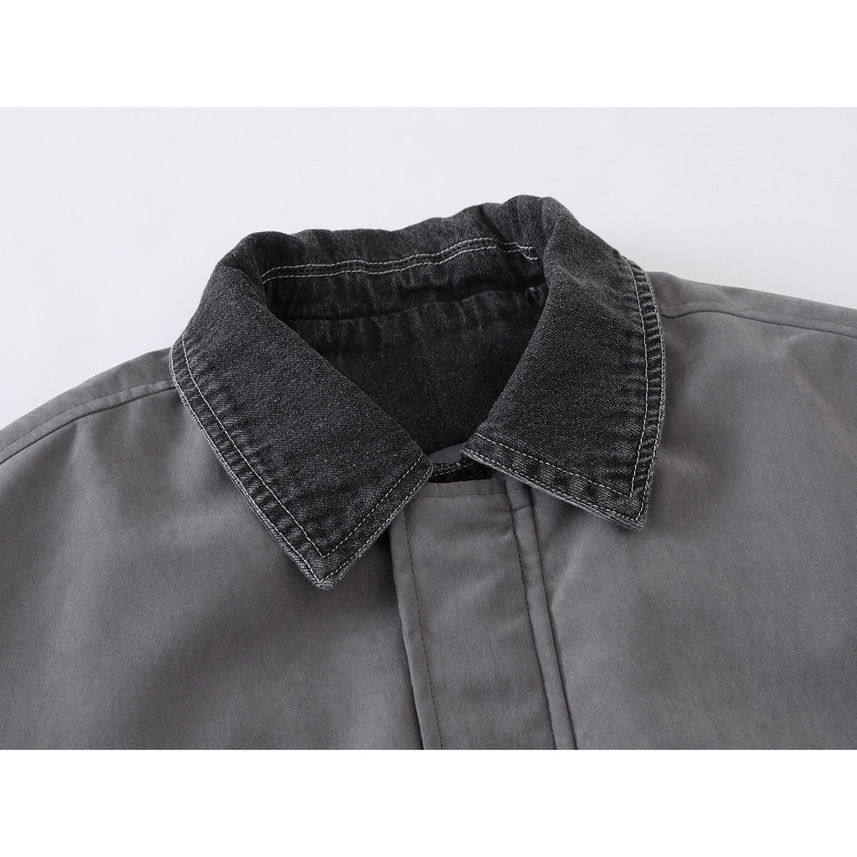 Close-up of a gray jacket with a dark washed-denim pointed collar and visible contrast stitching.