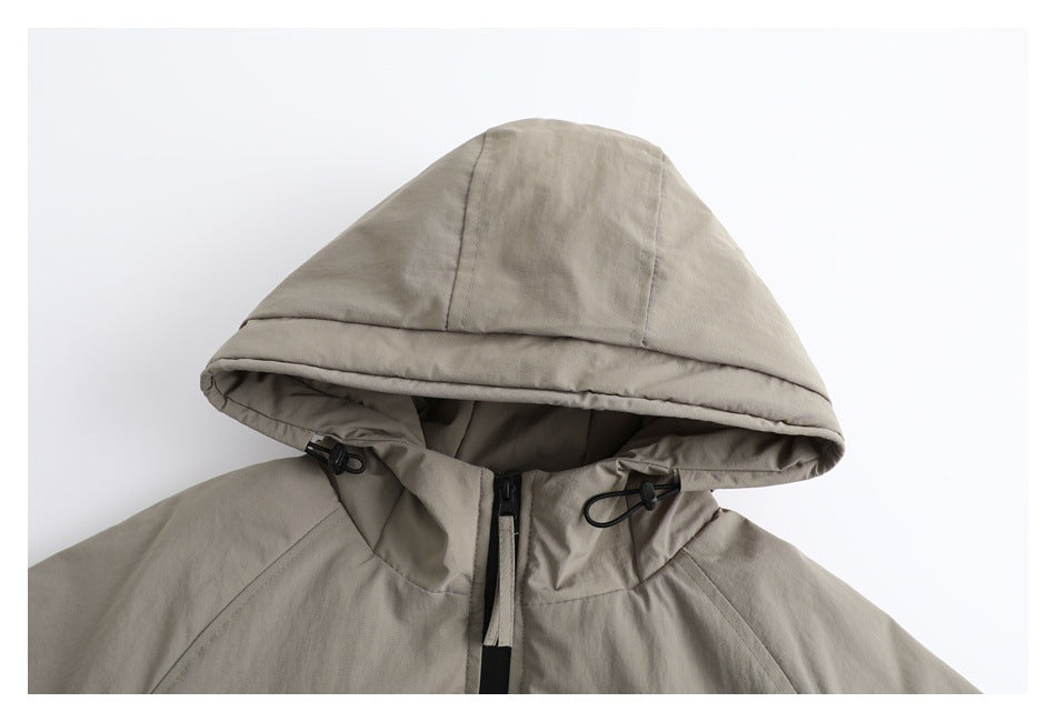 Close-up of the taupe jacket's hood, black drawcord toggles, and front zipper.