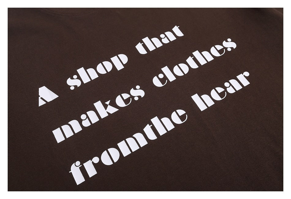 Close-up of white stencil-style text printed on a dark brown shirt.