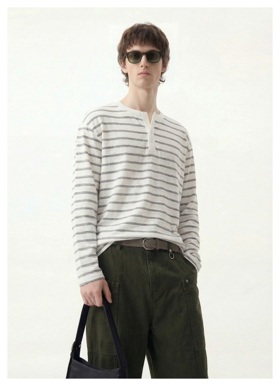 Closer front view of a model wearing a white and gray striped long-sleeve henley.