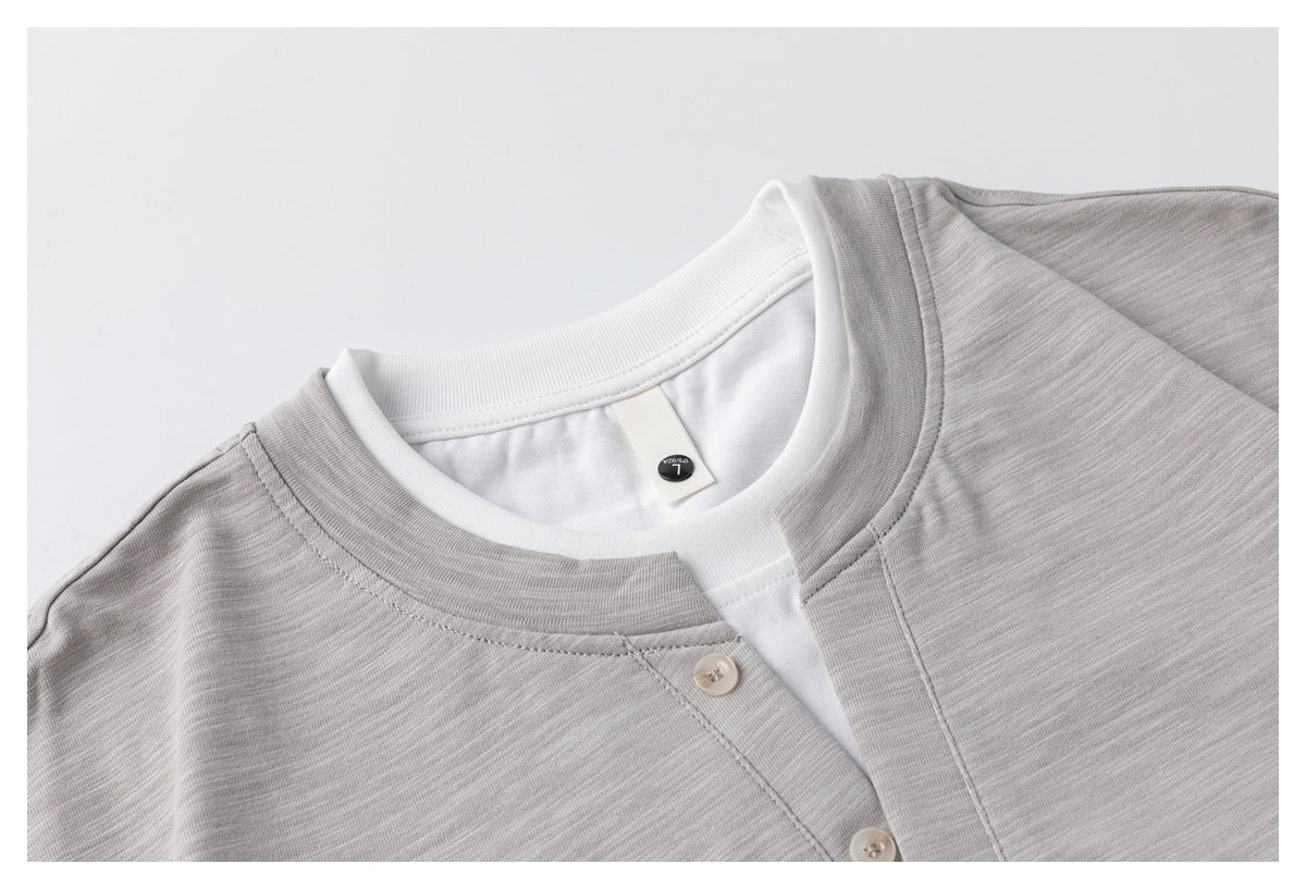 Close-up of the light gray shirt's round neckline and button placket layered over a white crew-neck shirt.