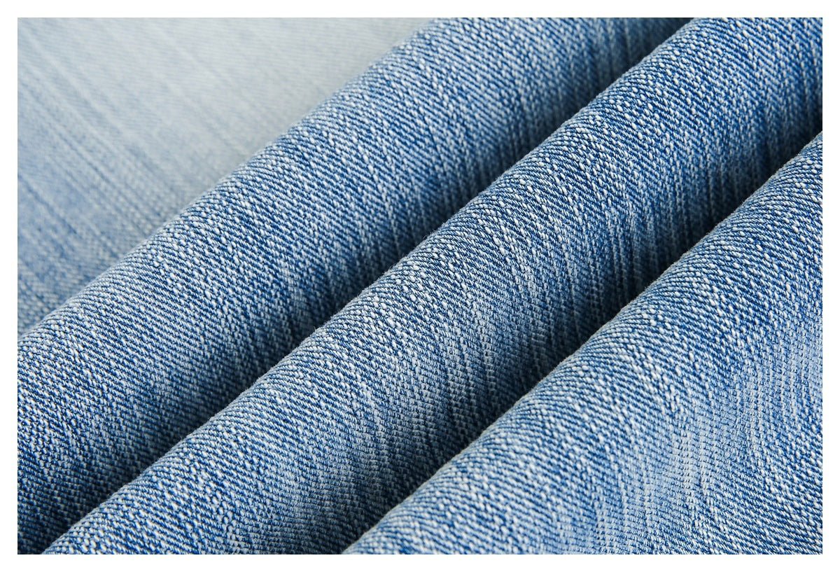 Macro view of blue denim fabric folded into ridges, showing its woven texture.