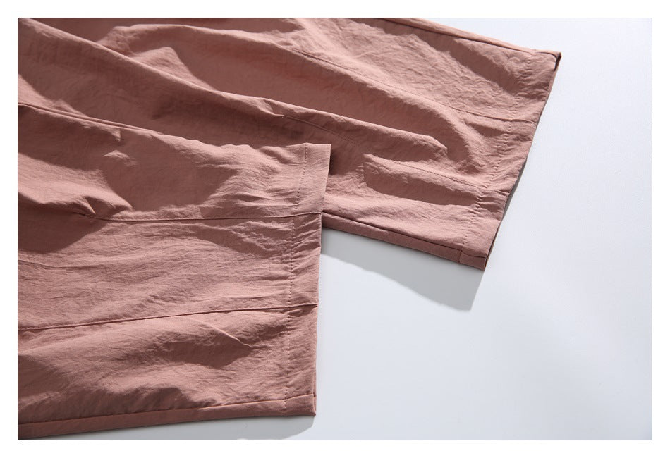 Close-up of dusty rose garment hems and stitched panels laid flat on a white background.