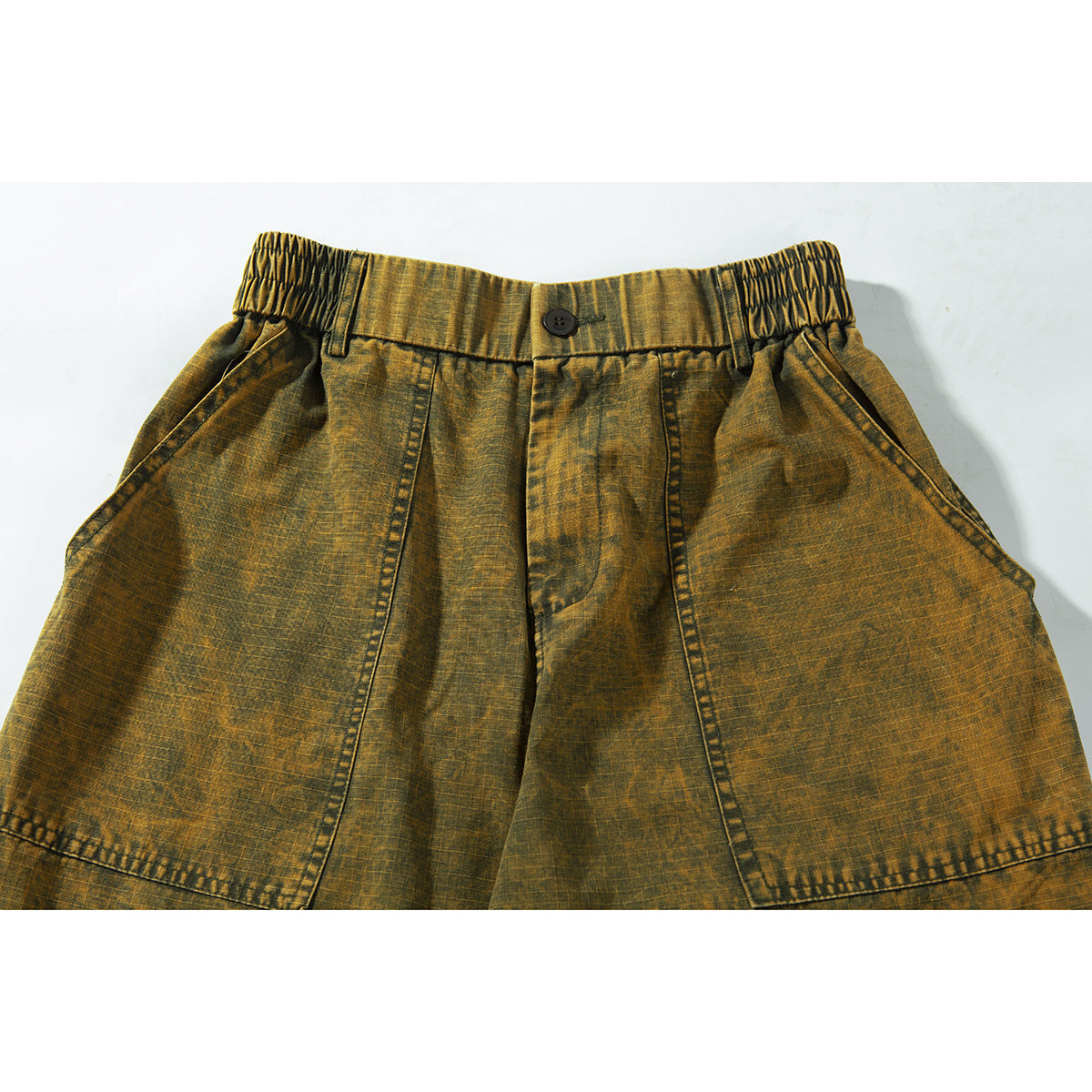 Close-up of ochre-brown wide-leg trousers showing the buttoned elastic-sided waist, front pockets and panel seams.