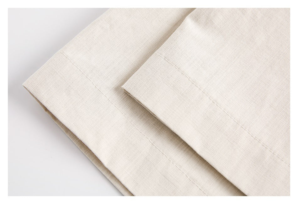 Close-up of a neatly stitched folded hem on plain cream fabric.