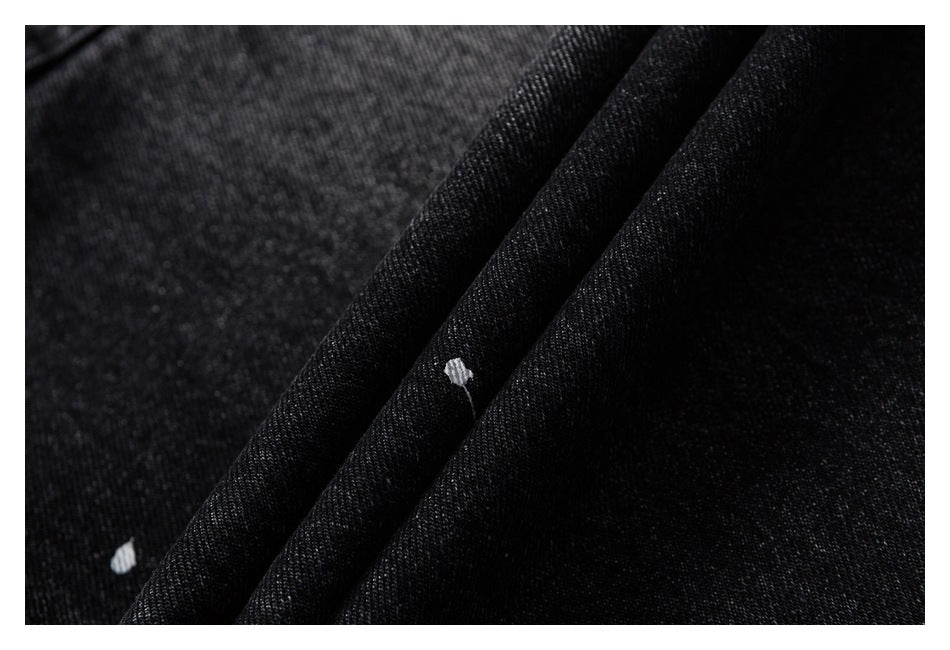 Macro view of textured black denim folds with small white paint-like marks.