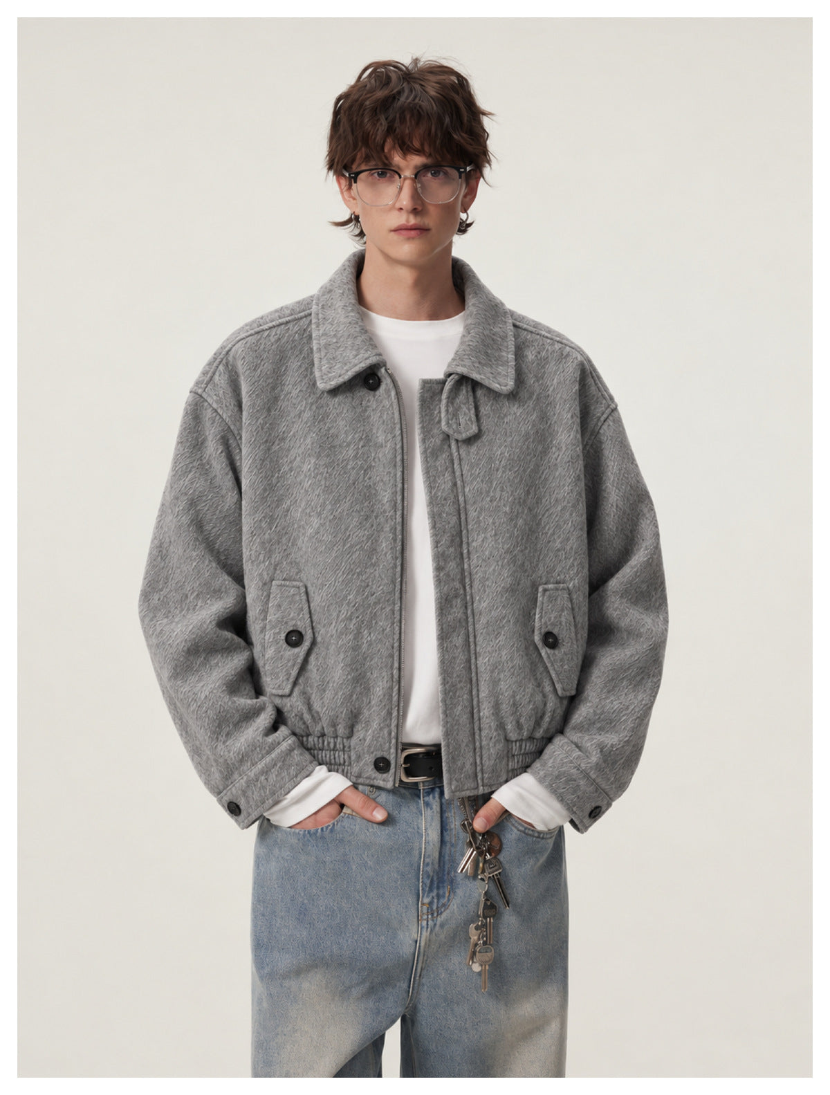Closer front view of a model wearing a gray textured jacket with a wide collar, dark buttons, and flap pockets.