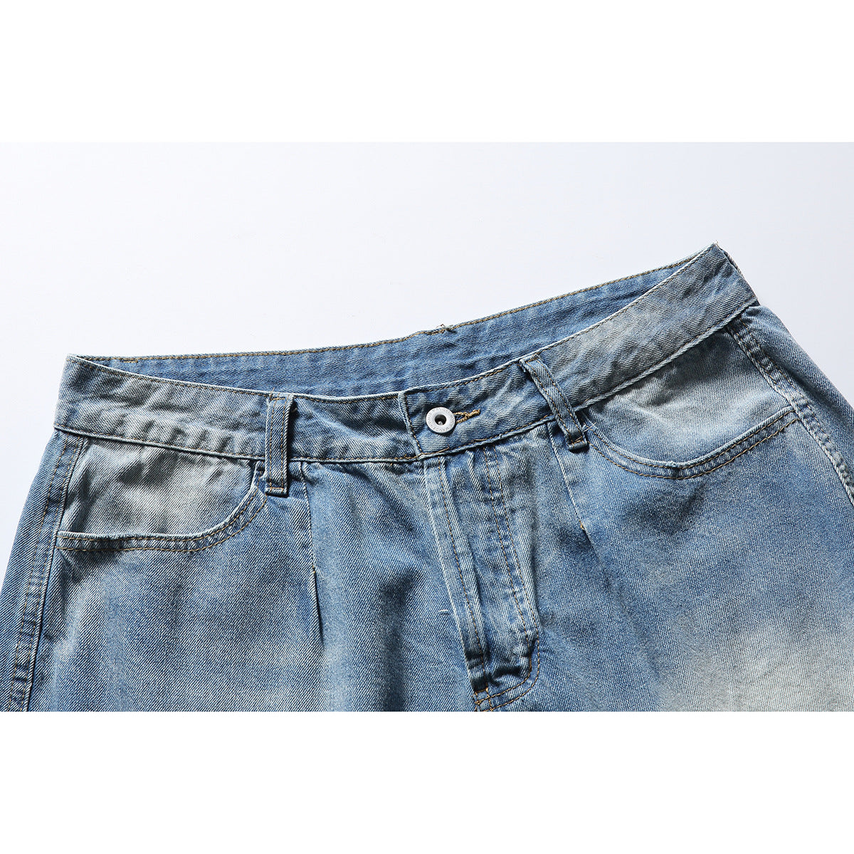 Close-up of the front waistband, button, pockets and faded blue wash of denim shorts.