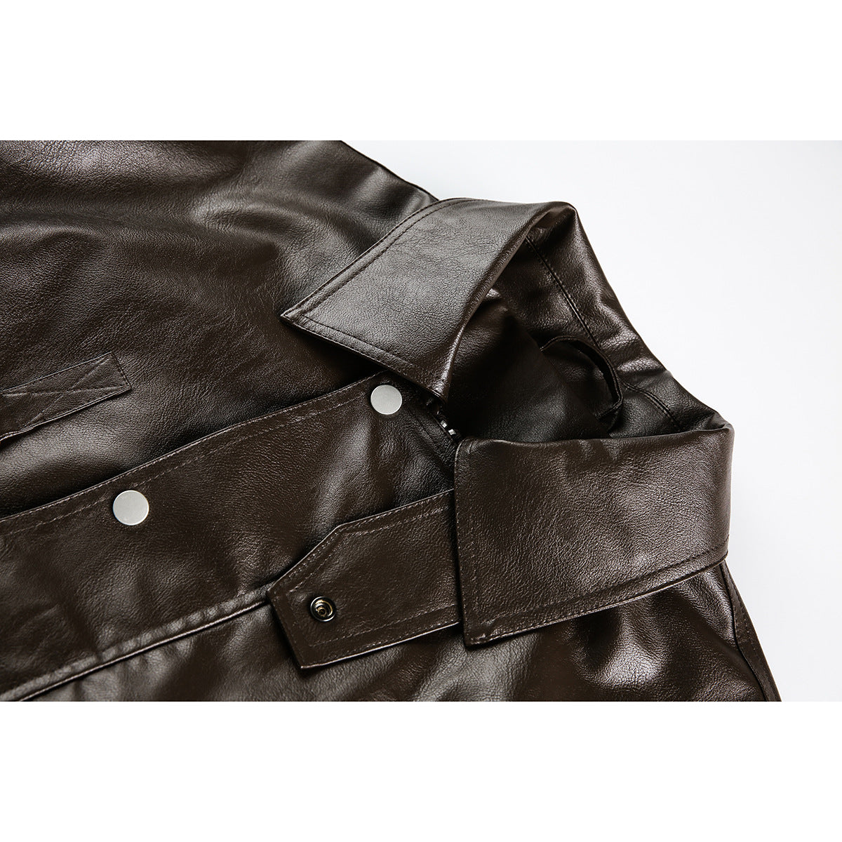 Close-up of a dark brown jacket collar, lapel, and silver snap fasteners.