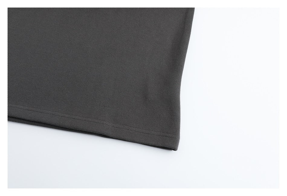 Close-up of the stitched hem on a dark charcoal garment against a light background.
