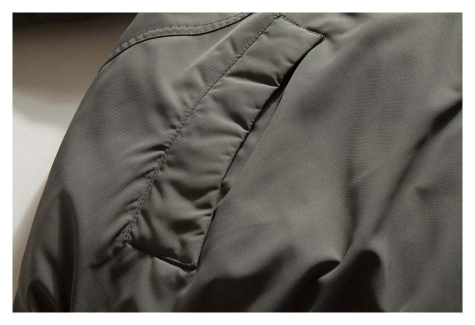 Close-up of a flap pocket and seam on the olive-gray jacket sleeve.